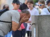 Un hombre se refresca en fuente p&uacute;blica.